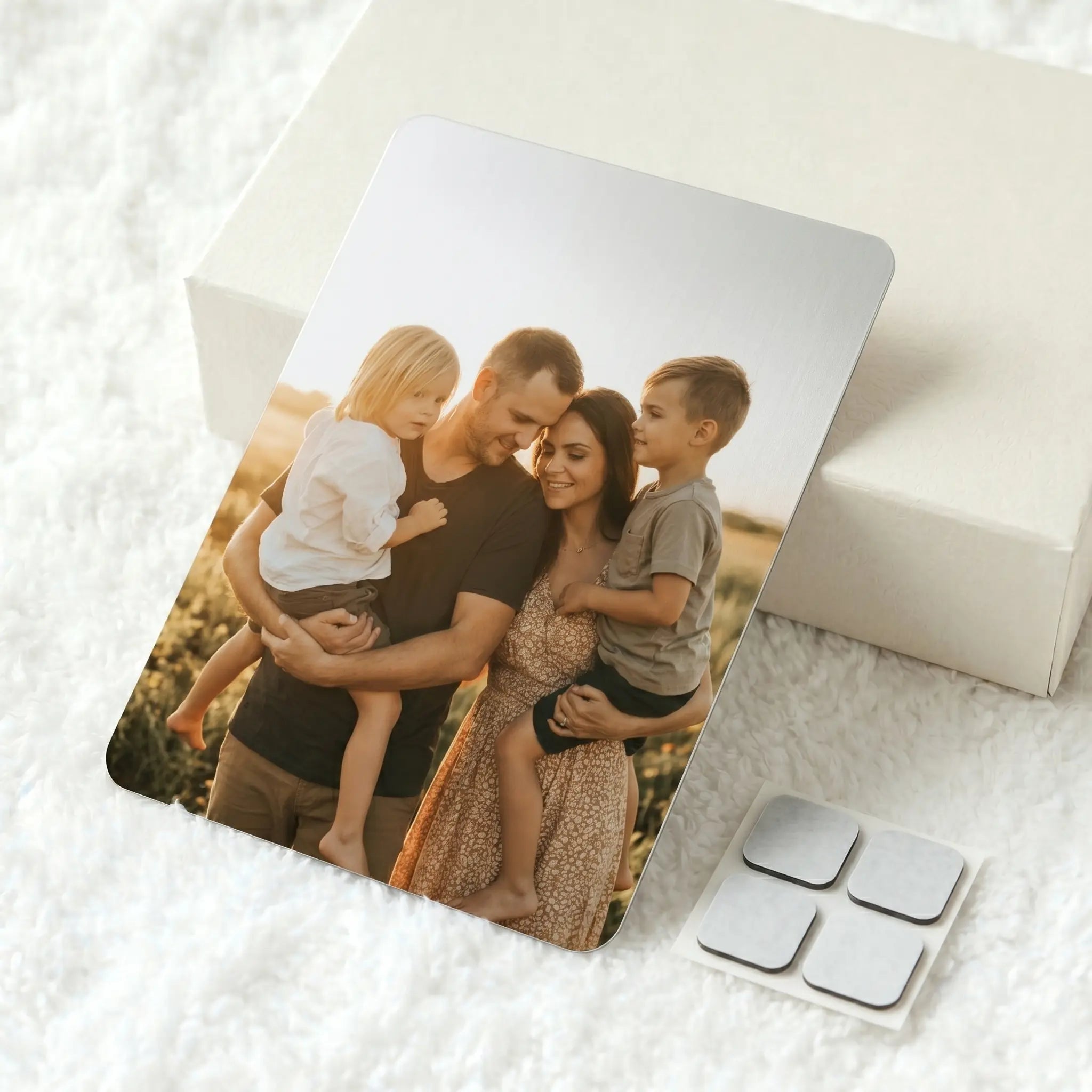 Custom A4 metal photo panel with family portrait print and adhesive hanging pads on soft white textured background