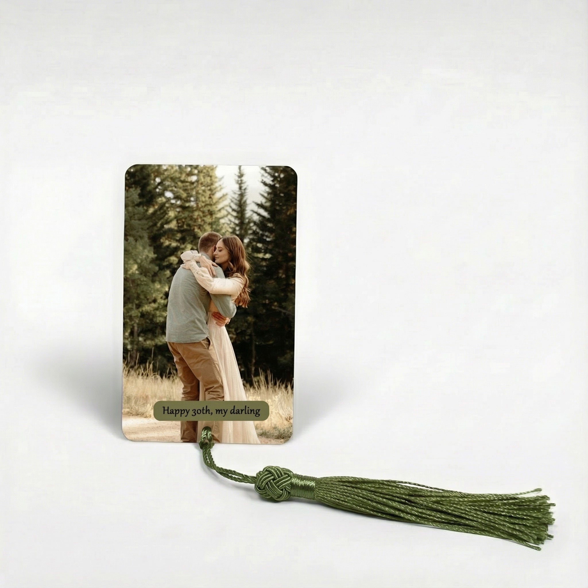 Personalised photo bookmark featuring a romantic couple in a forest printed on metal. Custom anniversary keepsake gift for him or her with green tassel.