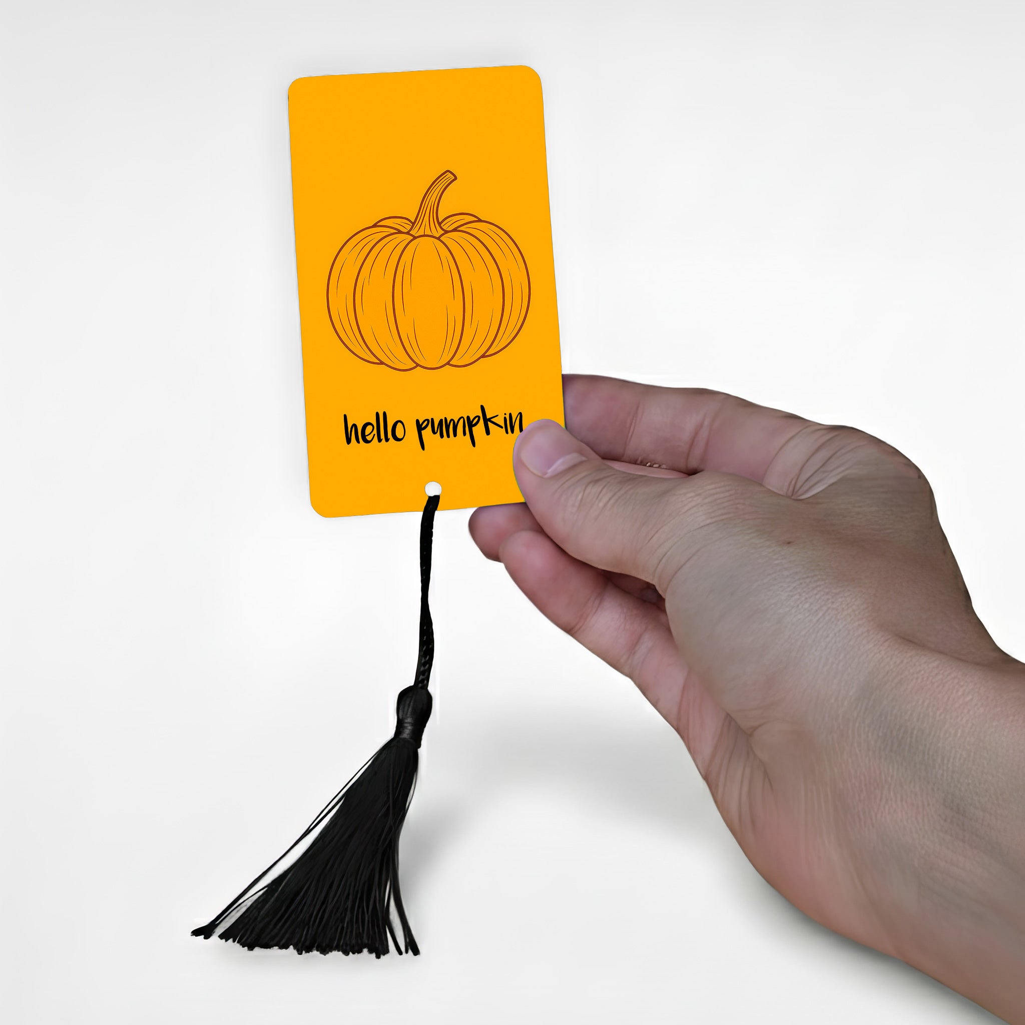 Minimalist orange metal bookmark with pumpkin illustration and “hello pumpkin” text, held in hand — personalised autumn bookmark gift for her, handmade in the UK.
