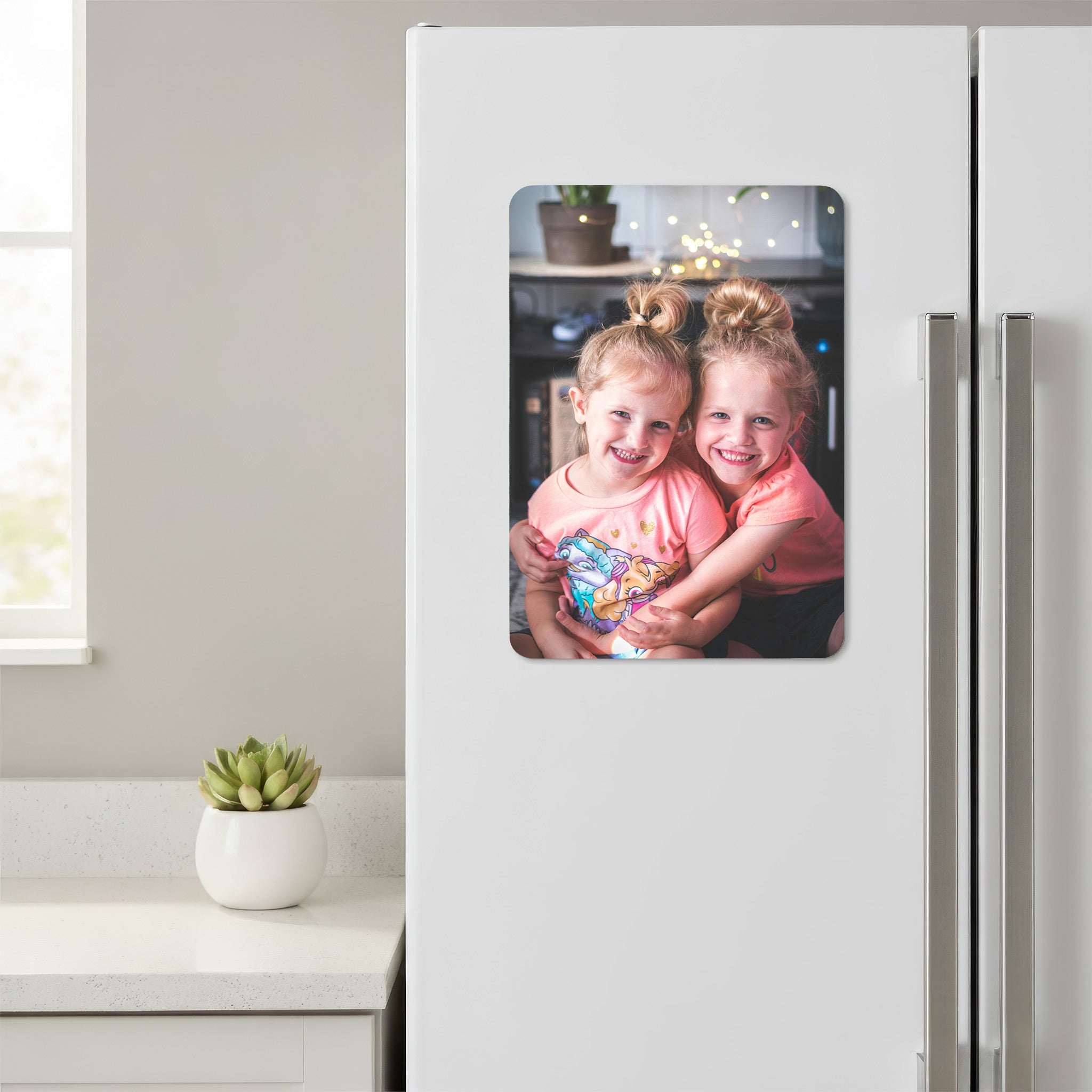 Personalised portrait photo fridge magnet featuring two smiling children, attached to a white kitchen fridge.