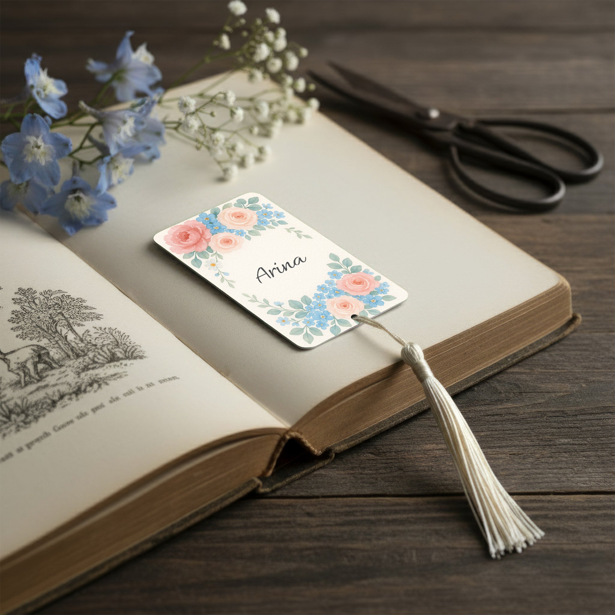 Custom floral name bookmark resting in open vintage book, English garden bouquet watercolour design with roses and forget-me-nots, romantic personalised gift for book lovers UK.