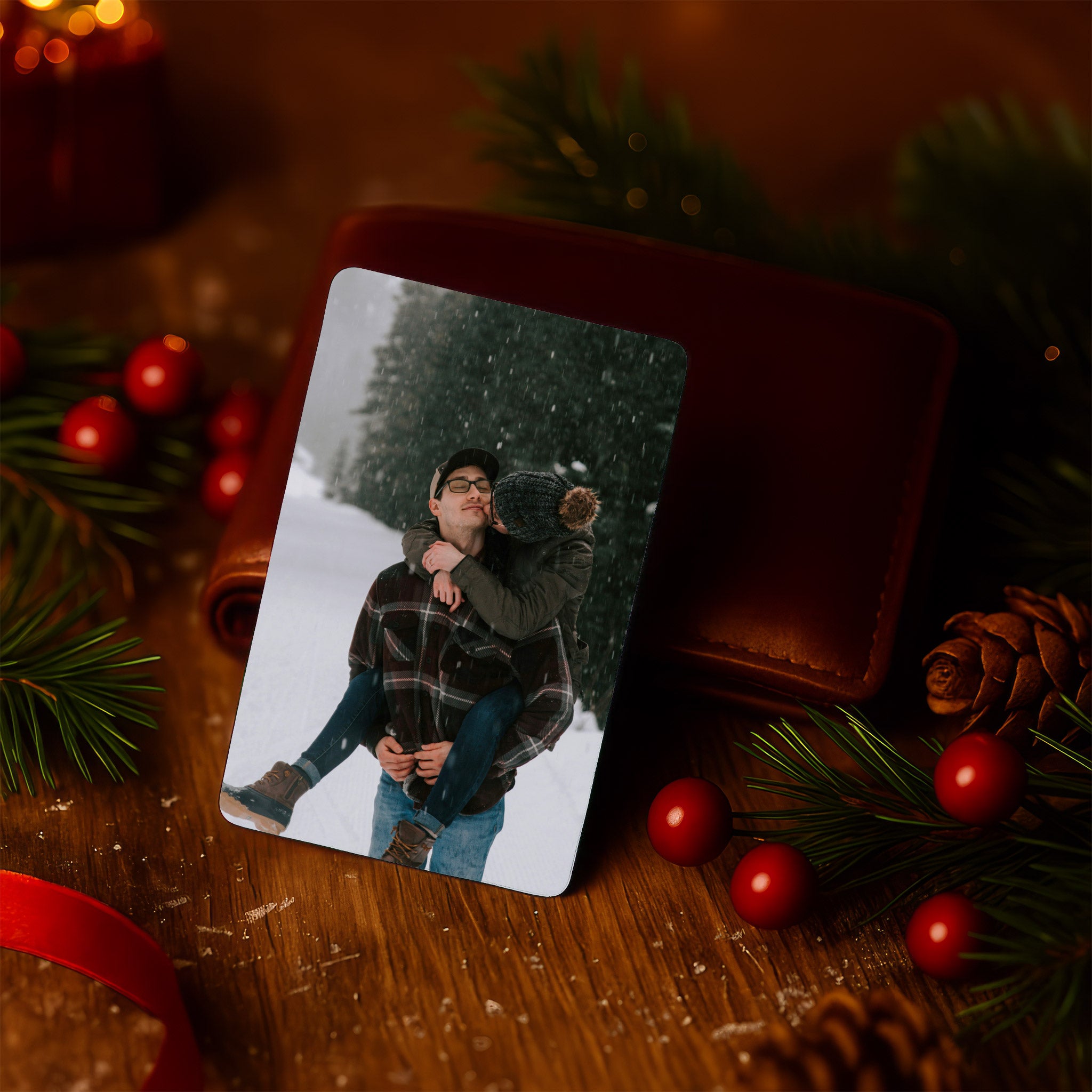 Romantic personalised photo wallet card resting on a brown wallet with Christmas lights and pine decorations — thoughtful Christmas gift for boyfriend or husband made in the UK.